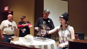 People playing a bingo-like game with a cage and numbered balls.