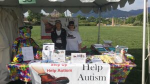 Two women at a booth signing up for help with autism awareness.