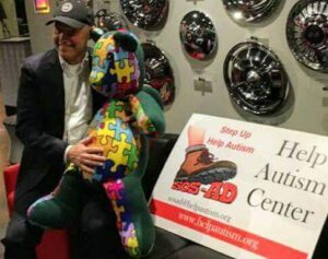 Man poses with colorful puzzle-piece sculpture at event.