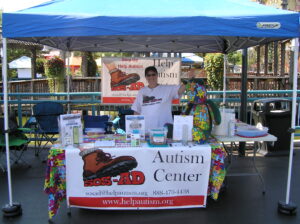 Autism Center awareness booth with informational materials and a volunteer.