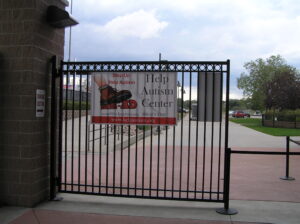 Black iron gate with a closed sign in a park area.