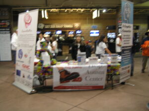 A busy vendor booth at an indoor market selling coffee and other items.