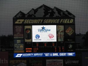Scoreboard at Security Service Field showing a game update and advertisements.