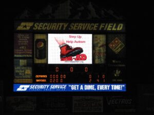 Baseball stadium scoreboard advertising security services and a sign for a 'Ship Up Ship Auction'.