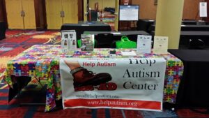 A Help Autism Center informational booth with brochures and a laptop.