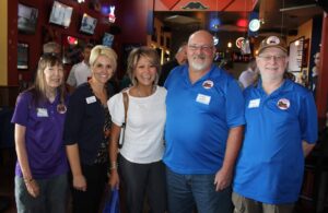 Group of four adults smiling at a social event indoors.