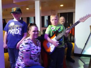 Group of people enjoying music with a boy playing electric guitar.